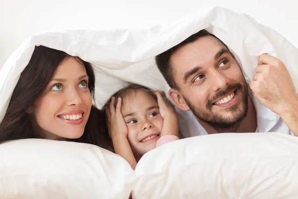 Heureux famille couché dans le lit sous couverture à la maison — Photo