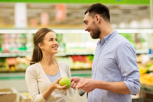 Feliz pareja comprar manzanas en la tienda de comestibles —  Fotos de Stock