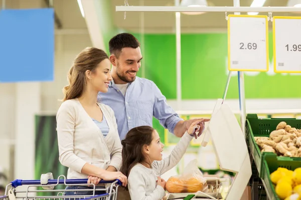 Familie met een gewicht van sinaasappelen op schaal in supermarkt — Stockfoto