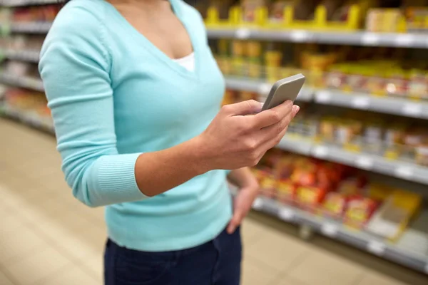 Женщина со смартфоном в магазине или супермаркете — стоковое фото