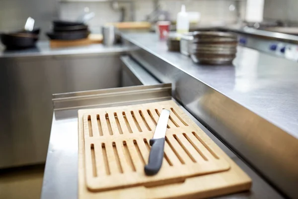 Cutting board and knife at restaurant kitchen — Stock Photo, Image