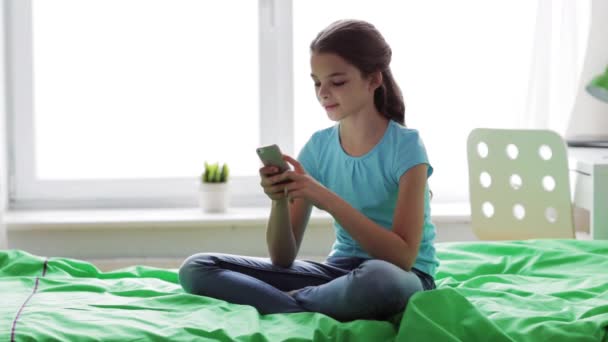 Glimlachend meisje sms 'en op smartphone thuis — Stockvideo