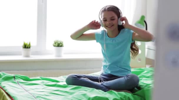 Chica feliz con teléfono inteligente y auriculares en casa — Vídeo de stock