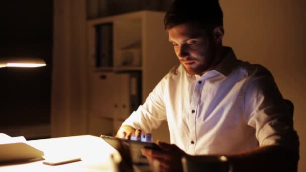 Человек с планшетным компьютером, работающий поздней ночью в офисе — стоковое видео