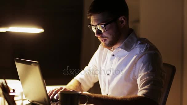 Человек с ноутбуком и кофе работает в ночном офисе — стоковое видео