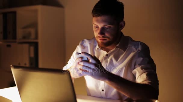 Человек с ноутбуком и смартфоном в ночном офисе — стоковое видео