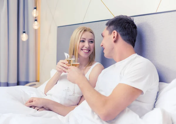 Улыбающаяся пара с бокалами шампанского в постели — стоковое фото