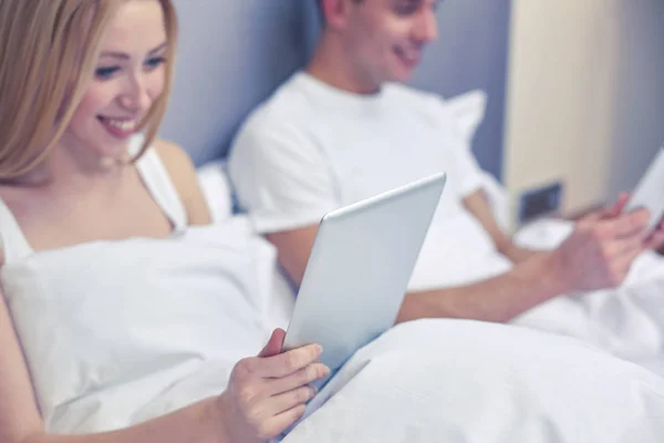 Lachende paar in bed met tablet pc-computers — Stockfoto