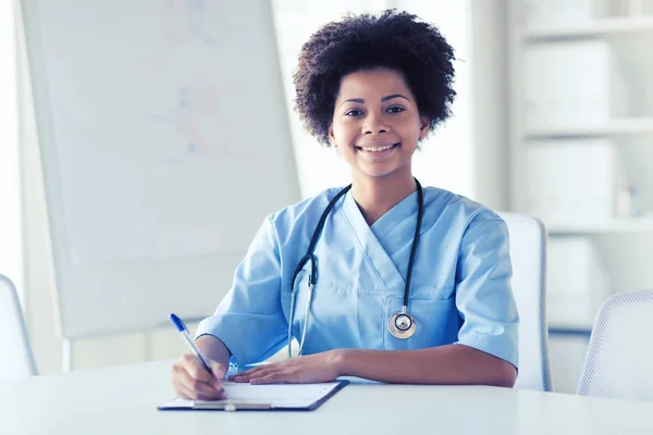 Médico ou enfermeira feliz escrevendo para a área de transferência — Fotografia de Stock