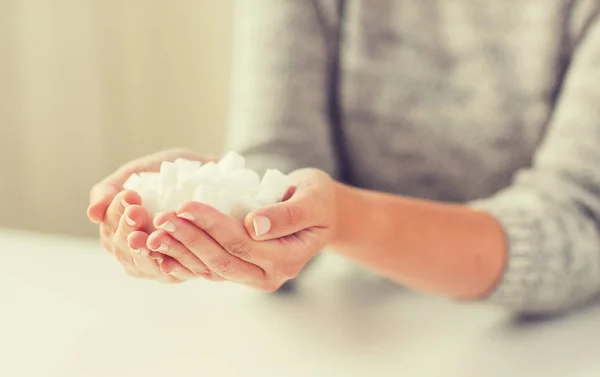 Perto de açúcar de caroço branco em mãos de mulher — Fotografia de Stock