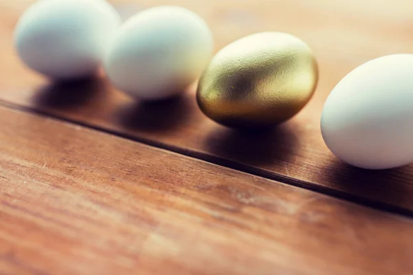 Close up of golden and white easter eggs on wood — Stock Photo, Image