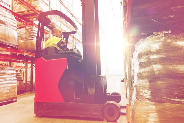 Man op de heftruck laden van vracht in magazijn — Stockfoto