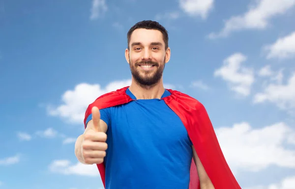 Šťastný muž v červených superhrdina cape ukazuje palec — Stock fotografie