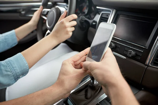 Hombre y mujer felices con smartphone conduciendo en coche —  Fotos de Stock