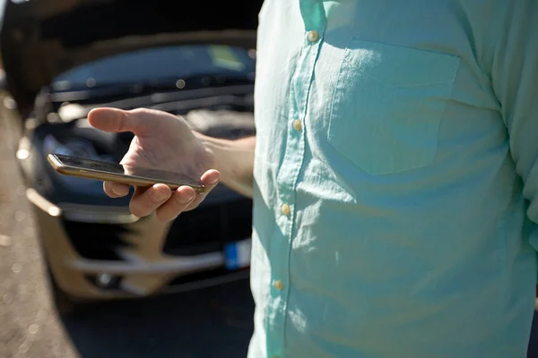 Close up de homem com smartphone e carro quebrado — Fotografia de Stock