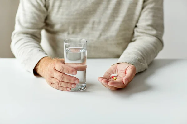 Perto de mãos com pílulas de medicina e água — Fotografia de Stock