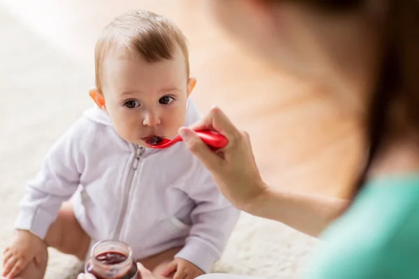 Madre con cuchara alimentando a un bebé en casa — Foto de Stock