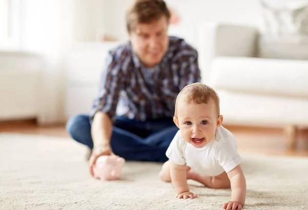 Lycklig far med baby och spargris hemma — Stockfoto