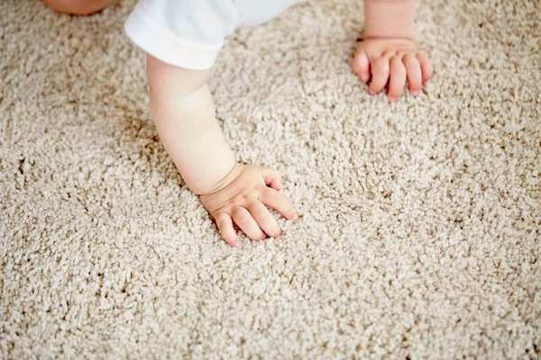 Hands of baby crawling on floor or carpet — Stock Photo, Image