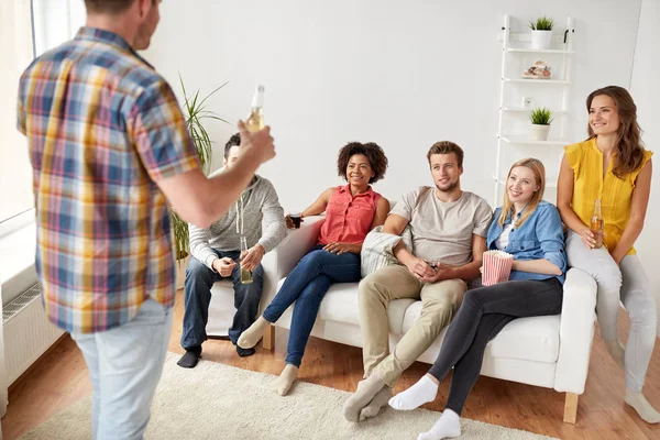 Amigos con palomitas de maíz y bebidas hablando en casa — Foto de Stock