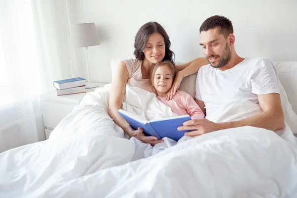 Glückliche Familie liest Buch zu Hause im Bett — Stockfoto