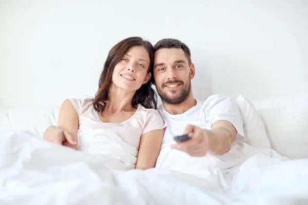 Lyckliga par i sängen hemma och tittar på tv — Stockfoto