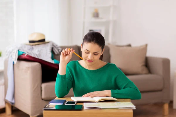 Mujer con cuaderno y mapa de viajes en casa — Foto de Stock