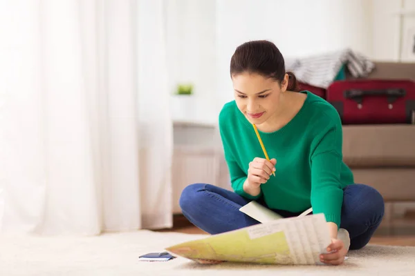 Mujer con cuaderno y mapa de viajes en casa — Foto de Stock