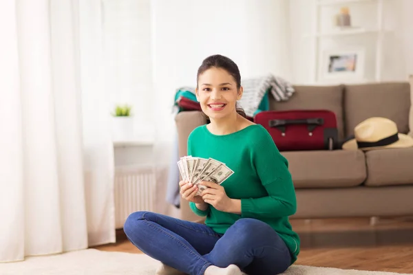 Mujer feliz con dinero y bolsa de viaje en casa — Foto de Stock