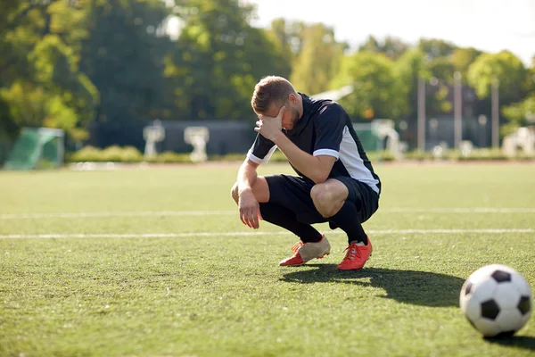 Грустный футболист с мячом на футбольном поле — стоковое фото