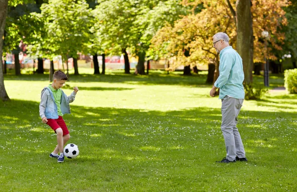 Velho homem e menino jogando futebol no parque de verão — Fotografia de Stock