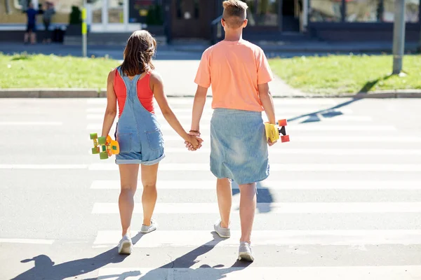 Pareja adolescente con patinetas en la ciudad crosswalk — Foto de Stock