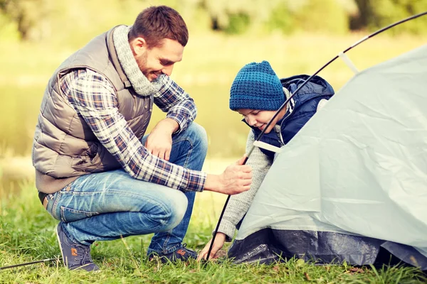 Happy father and son setting up tent outdoors — Stock Photo, Image