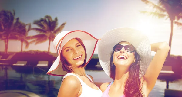 Χαμογελώντας νεαρές γυναίκες σε καπέλα στην παραλία — Φωτογραφία Αρχείου
