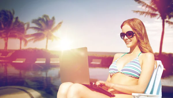 Happy young woman in shades with laptop on beach — Stock Photo, Image