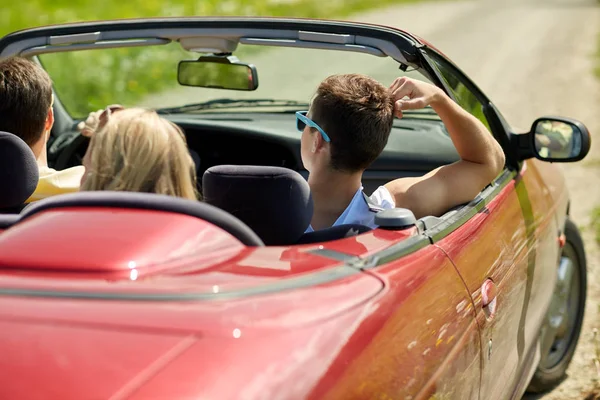 Amigos felizes dirigindo em carro conversível no verão — Fotografia de Stock