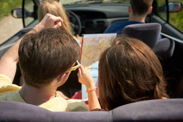 Amigos felizes com mapa dirigindo em carro conversível — Fotografia de Stock