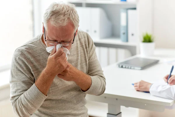 Senior man blowing nose with napkin at hospital — Stock Photo, Image