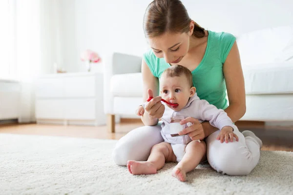 Mutter mit Löffel füttert kleines Baby zu Hause — Stockfoto