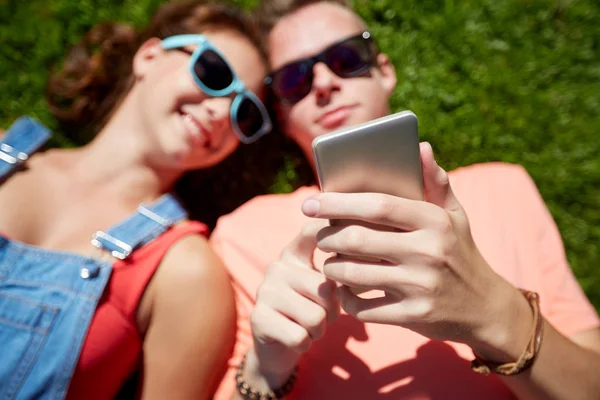 Couple adolescent avec smartphone couché sur l'herbe — Photo