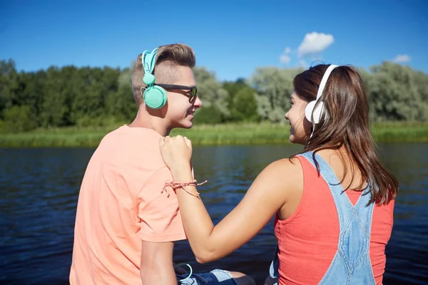 Pareja adolescente con auriculares en la litera del río —  Fotos de Stock