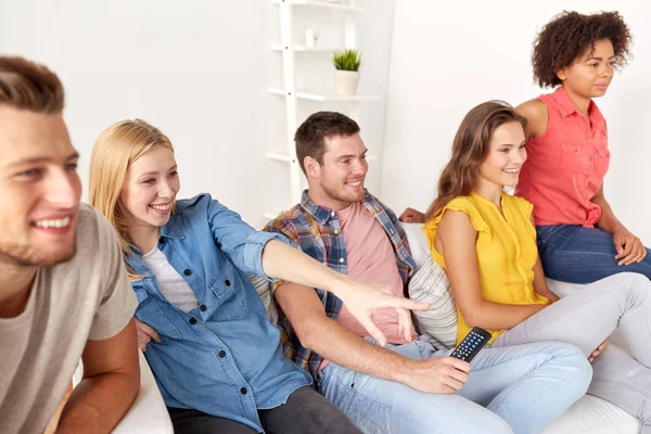 Amigos felizes com controle remoto assistindo tv em casa — Fotografia de Stock