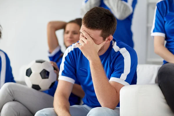 Homem infeliz com amigos ou fãs de futebol em casa — Fotografia de Stock