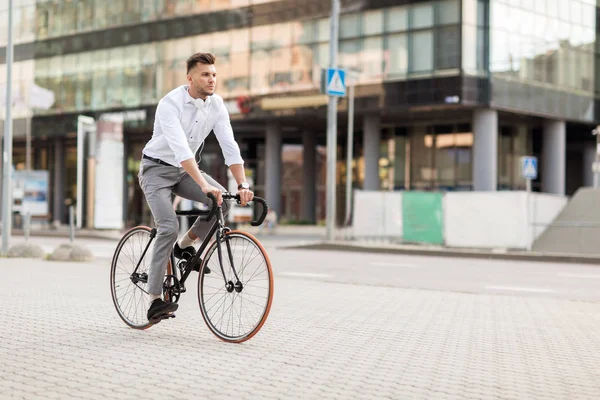 Человек с наушниками на велосипеде по улице города — стоковое фото