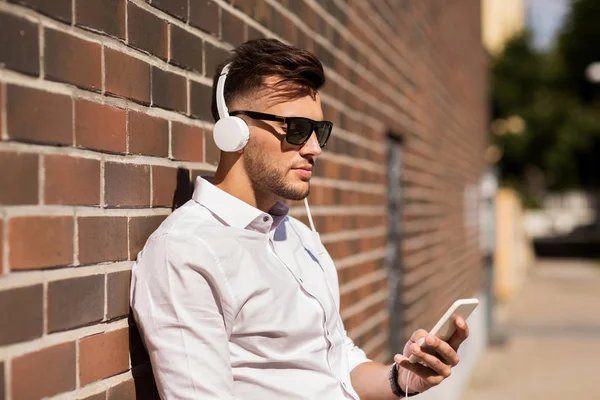 Homem com fones de ouvido e smartphone ouvindo música — Fotografia de Stock