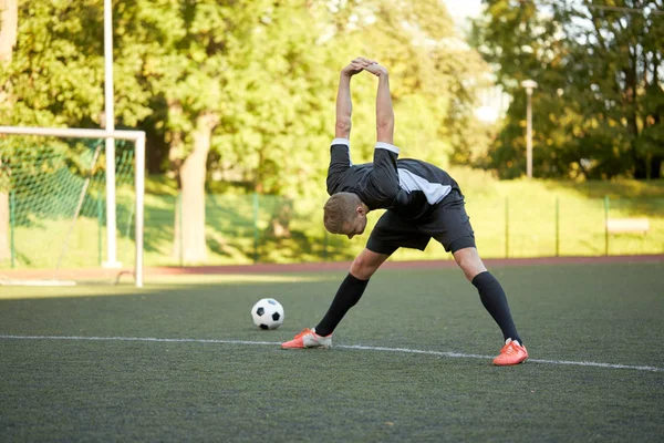 Jogador de futebol esticando a perna no campo de futebol — Fotografia de Stock