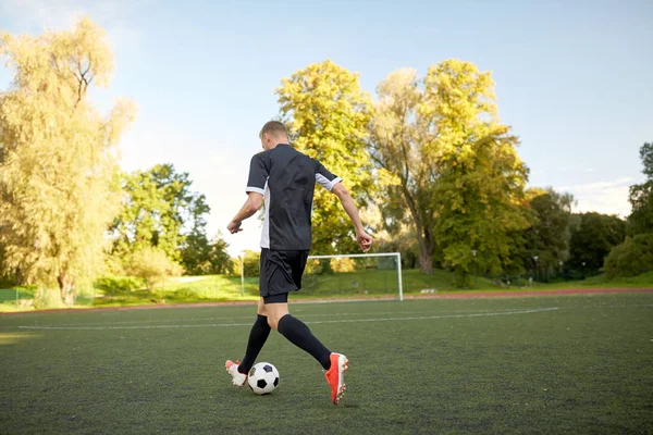 Fotbalový hráč hraje s míčem na fotbalové hřiště — Stock fotografie