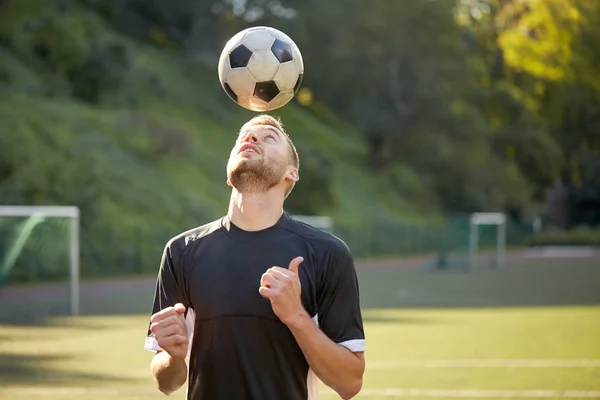 Футболист играет с мячом на поле — стоковое фото
