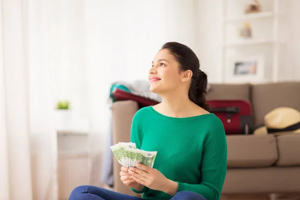 Mujer feliz con dinero y bolsa de viaje en casa — Foto de Stock