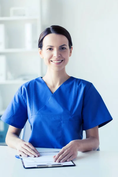 Glücklicher Arzt oder Krankenschwester mit Klemmbrett im Krankenhaus — Stockfoto